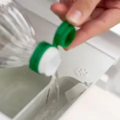 Essig wird in das Waschmittelfach der Waschmaschine gegossen, um Wäsche aufzufrischen und Kalk zu entfernen.