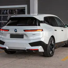 Białe BMW iX z czarnymi akcentami stoi na parkingu.