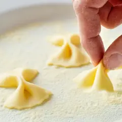 Hand formt Farfalle-Nudeln in einer Schüssel mit feiner farina di semola.