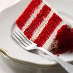 Una fetta di torta Red Velvet, con strati rossi e crema bianca, pronta per essere gustata. La ricetta perfetta per un dolce indimenticabile.