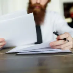 Hombre con barba revisa documentos, evaluando la validez del contrato de alquiler sin registrar.