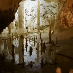 Stalattiti e stalagmiti riflettono in uno specchio d'acqua nelle grotte di Frasassi, dove si trovano meraviglie naturali.