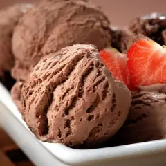 Cremoso helado de chocolate servido en un cuenco blanco, decorado con fresas frescas.