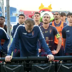 Piłkarze Pogoni Szczecin w granatowych strojach stoją w rzędzie, patrząc w dół.