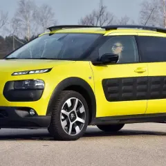 Żółty Citroen Cactus z czarnymi wstawkami na drzwiach i relingami dachowymi, zaparkowany na drodze.
