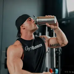 Uomo con muscoli scolpiti beve da un shaker, pronto per la sua integrazione con berberina per massimizzare i risultati.
