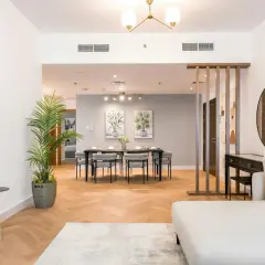A modern living and dining area, showcasing excellent real estate photography lighting. The space features a sofa, dining table, and decorative elements.