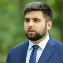 Młody mężczyzna w garniturze, Jakubas Banaszek, budzi zaskoczenie działaczy swoją kandydaturą na premiera.