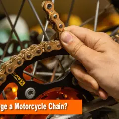 Mano sujetando una cadena dorada de moto, lista para cambiarla.