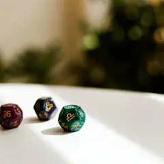 Trzy kostki do gry z symbolami zodiaku. Jedna, fioletowa, pokazuje liczbę 6, co może sugerować numerologiczną 6.