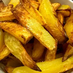 Chrupiące frytki z airfryer, posypane solą, w białej misce. Idealna przekąska, która zachwyca smakiem i wyglądem.