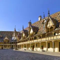 Cour intérieure des Hospices de Beaune, un joyau architectural à visiter. Toits colorés, arcades et pavés de pierre.