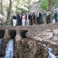 Un grupo de personas celebra en el lugar donde nace el río Andarax, con cascadas cayendo bajo un puente de piedra.