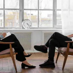 Una donna con occhiali ascolta attentamente un uomo che parla, prendendo appunti. Un sessuologo cosa fa: aiuta a risolvere problemi relazionali e intimi.