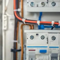 Profesjonalne wykonywanie instalacji elektrycznych: przewody w skrzynce rozdzielczej, bezpieczniki i zaciski.