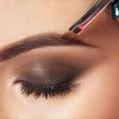Aplicando el toque final al maquillaje de cejas con un pincel.