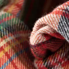 Miękka tkanina twill w kratę, z dominującymi kolorami czerwonym, żółtym i zielonym, tworzy przytulny wzór.