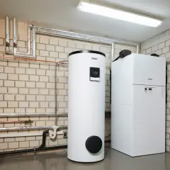Nowoczesny zasobnik do pieca gazowego marki Vaillant obok kotła. Instalacja grzewcza w kotłowni.