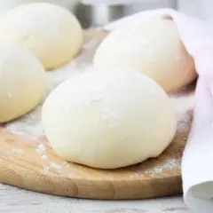Kulki ciasta na pizzę, posypane mąką, leżą na desce. Zastanawiasz się, czy można mrozić ciasto na pizzę? Tak, można!