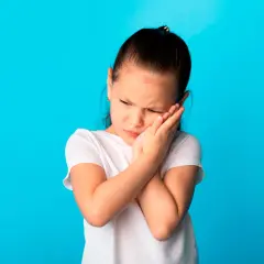 Niña con dolor de mejilla, posible síntoma de paperas en niños.
