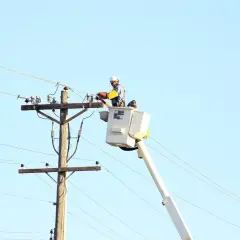 Elektryk wysokich napięć w podnośniku pracuje przy linii energetycznej.
