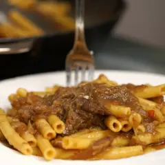 Un piatto invitante di ziti alla genovese, con la pasta condita da un ricco ragù di carne e cipolle.