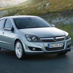 Srebrny Opel Astra GTC z kierowcą za kierownicą pokonuje zakręt na górskiej drodze.