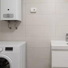 Czujnik czadu zamontowany na ścianie nad pralką i podgrzewaczem wody. W łazience znajduje się też umywalka.