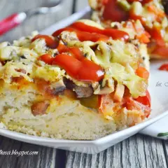 Pyszna pizza na grubym cieście z serem, pieczarkami i pomidorami, polana ketchupem.