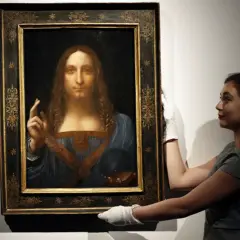 Frau mit weißen Handschuhen präsentiert das Gemälde "Salvator Mundi" von Leonardo da Vinci.