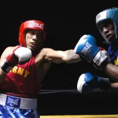 Boxer in red throws a left hook, demonstrating why is the left hook so devastating. His opponent in blue braces for impact.