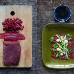 Förberedelser för asiatisk råbiff: rått kött i bitar och skivor på en skärbräda, färdig rätt med garnering på en grön tallrik.