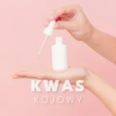 Dwie dłonie trzymają białą buteleczkę z pipetką, z której kapie płyn. Napis "KWAS KOJOWY" sugeruje jego działanie rozjaśniające.