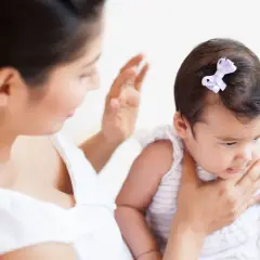 Mamma aiuta il suo neonato a fare il ruttino, con una mano sulla schiena del piccolo.