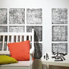 Abstrakte Muster auf der **Struktur Wand** über einer weißen Bank mit bunten Kissen und einem Tisch voller Dominosteine.