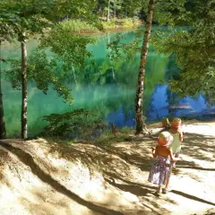 Dwie dziewczynki w słomkowych kapeluszach idą ścieżką nad turkusowe jezioro. Idealne miejsce, gdzie w góry z dziećmi.