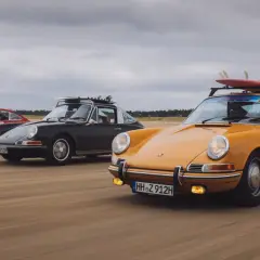 Trzy klasyczne Porsche 911 na plaży, żółte z deskami surfingowymi na dachu. Niesamowita fotografia samochodowa.