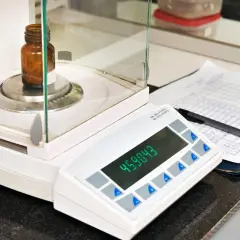 Waga laboratoryjna z buteleczką, wyświetlaczem i notatkami.
