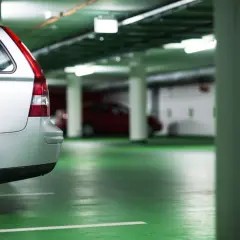 Voiture argentée dans un parking souterrain. Le sol est vert vif. On dirait que le propriétaire prépare une lettre préavis garage 1 mois.