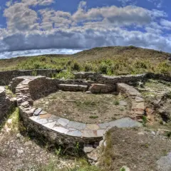 Ruinas circulares de piedra del castro de Formigueiros, con muros bajos y un patio central.