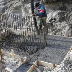 Wylany beton w szalunku, pracownik wylewa masę, mimo że czuć już przymrozek.