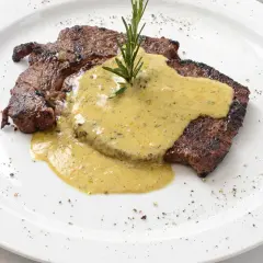 Un steak grillé, nappé d'une sauce crémeuse et garni d'une branche de romarin. Parfait pour accompagner une sauce pour entrecôte au barbecue.
