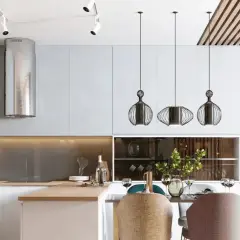 Cocina moderna con campana extractora plateada, lámparas colgantes de diseño y una mesa lista para cenar. La iluminación ambiental crea una atmósfera acogedora, con suficientes **lúmenes por m2** para cada actividad.