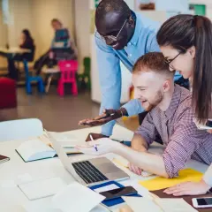 Studenci pracują nad projektem z cyberbezpieczeństwa. W tle biblioteka.