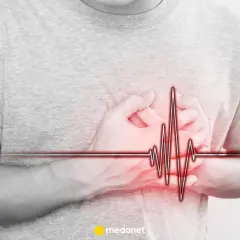 Osoba trzyma się za serce, na którym widnieje wykres EKG. Może to symbolizować problemy z sercem, jak np. arytmia, lub po prostu stres.