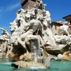 La Fontana dei Quattro Fiumi di Bernini, con le sue maestose statue che rappresentano i fiumi del mondo, zampilla sotto il cielo azzurro di Roma.