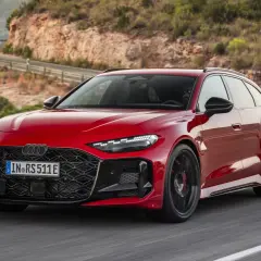 Czerwone Audi RS 7 pokonuje zakręt na malowniczej, górskiej drodze.