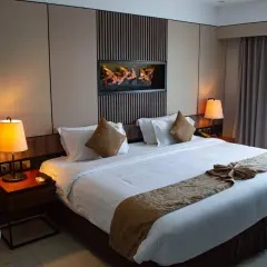 Elegancka sypialnia w stylu hotelowym z dużym łóżkiem, ozdobnym bieżnikiem i obrazem z ptakami nad wezgłowiem.