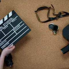 Kamera filmowa, klaps z napisem "Universal Studios" i obiektywy. To wszystko, co potrzebne do stworzenia opisu filmu po angielsku.