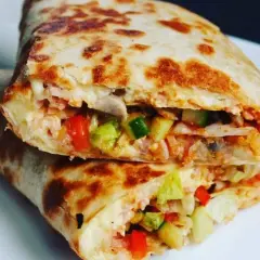 Złocista tortilla z jajkiem, serem i szynką, wypełniona warzywami, usmażona na patelni. Pyszne danie na szybki posiłek.